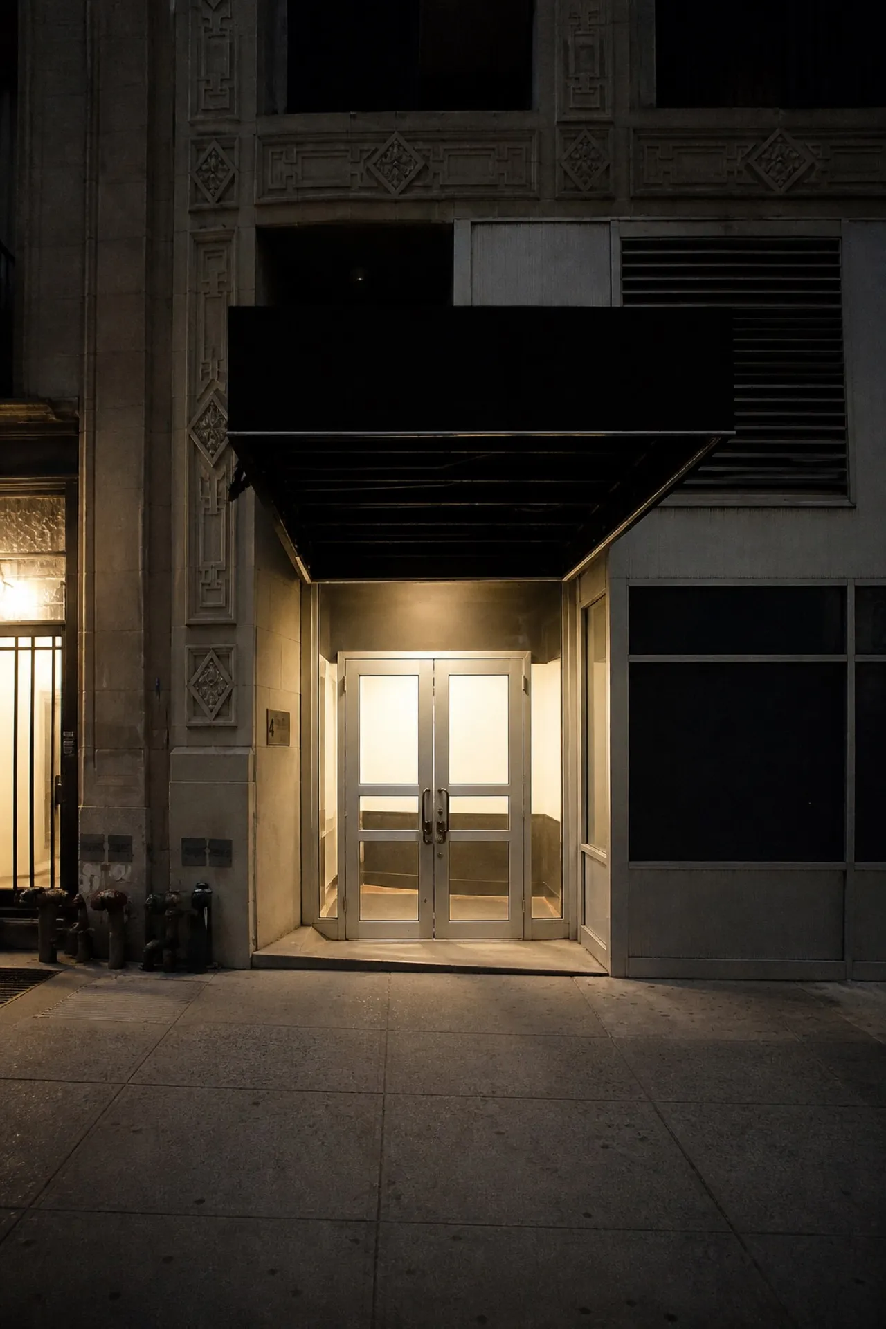 Small comedy venue frontage at night with lit entrance and dark upper floors