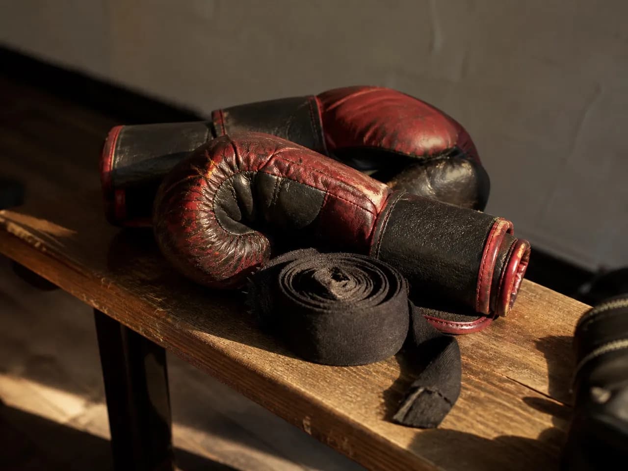 Worn boxing gloves and wraps on a bench