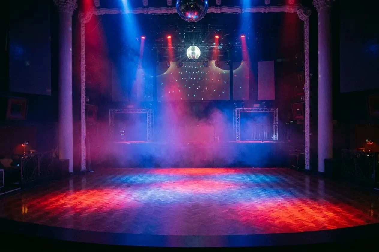 An empty dance floor lit from above in red and blue with haze in the air