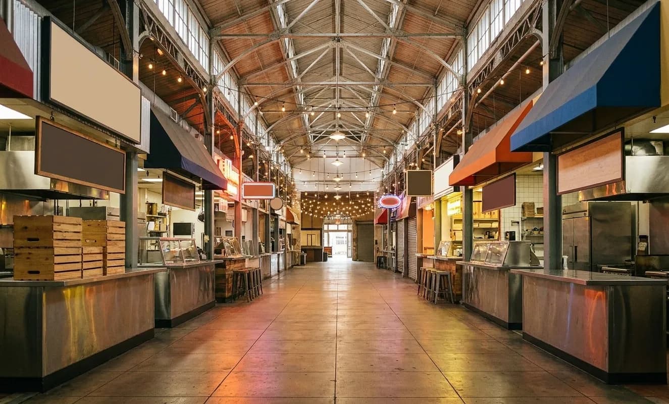 An indoor market hall lined with small food counters under hanging lights