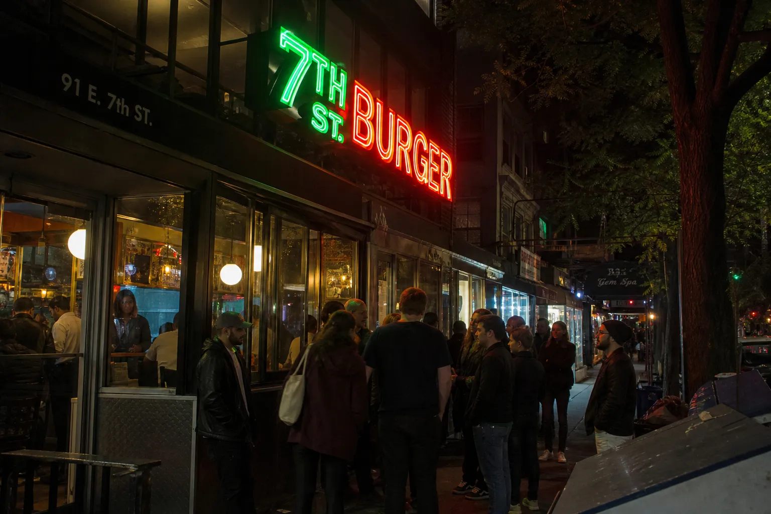 A narrow view looking down the order counter of a busy Manhattan smashburger joint, mimicking a crowded market aisle with patrons waiting for their food.