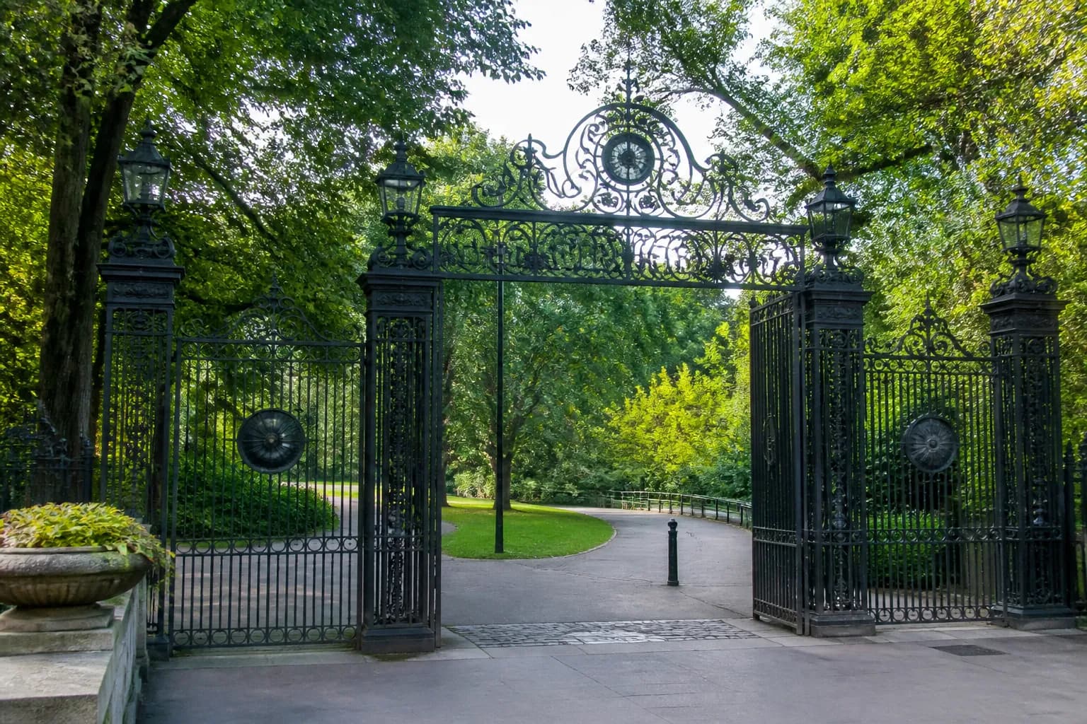 The rustic wooden facade of Cop Cot pavilion in Central Park surrounded by lush green trees and framed by distant Manhattan skyscrapers.