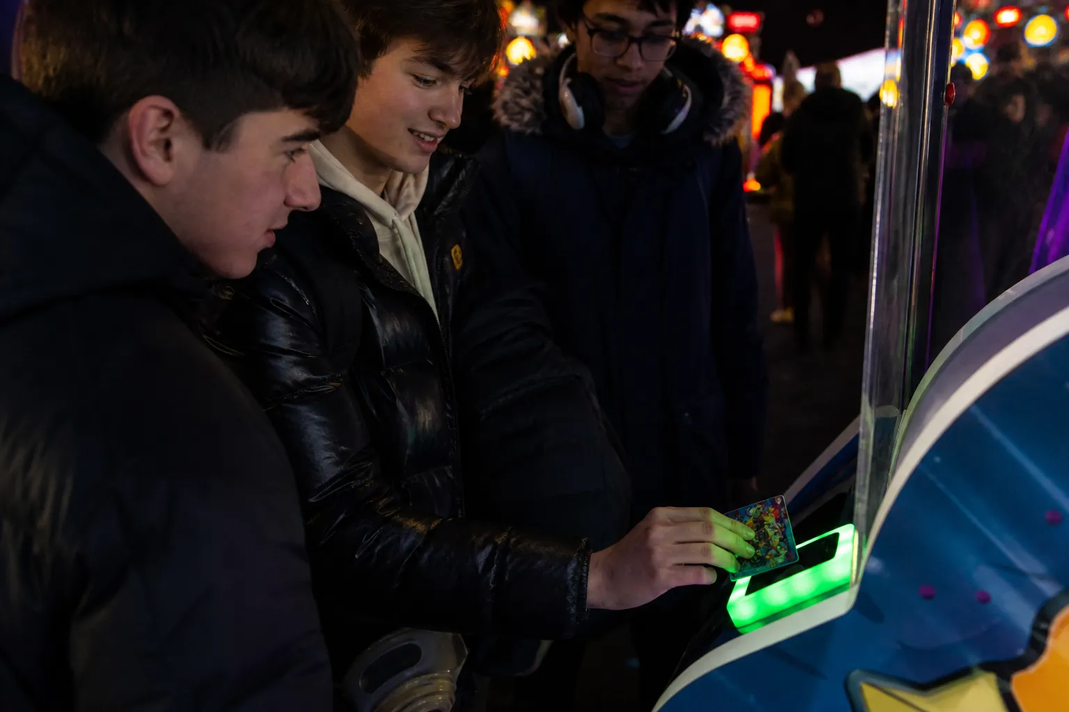 A hand tapping a digital Power Card on a neon-lit arcade game scanner.