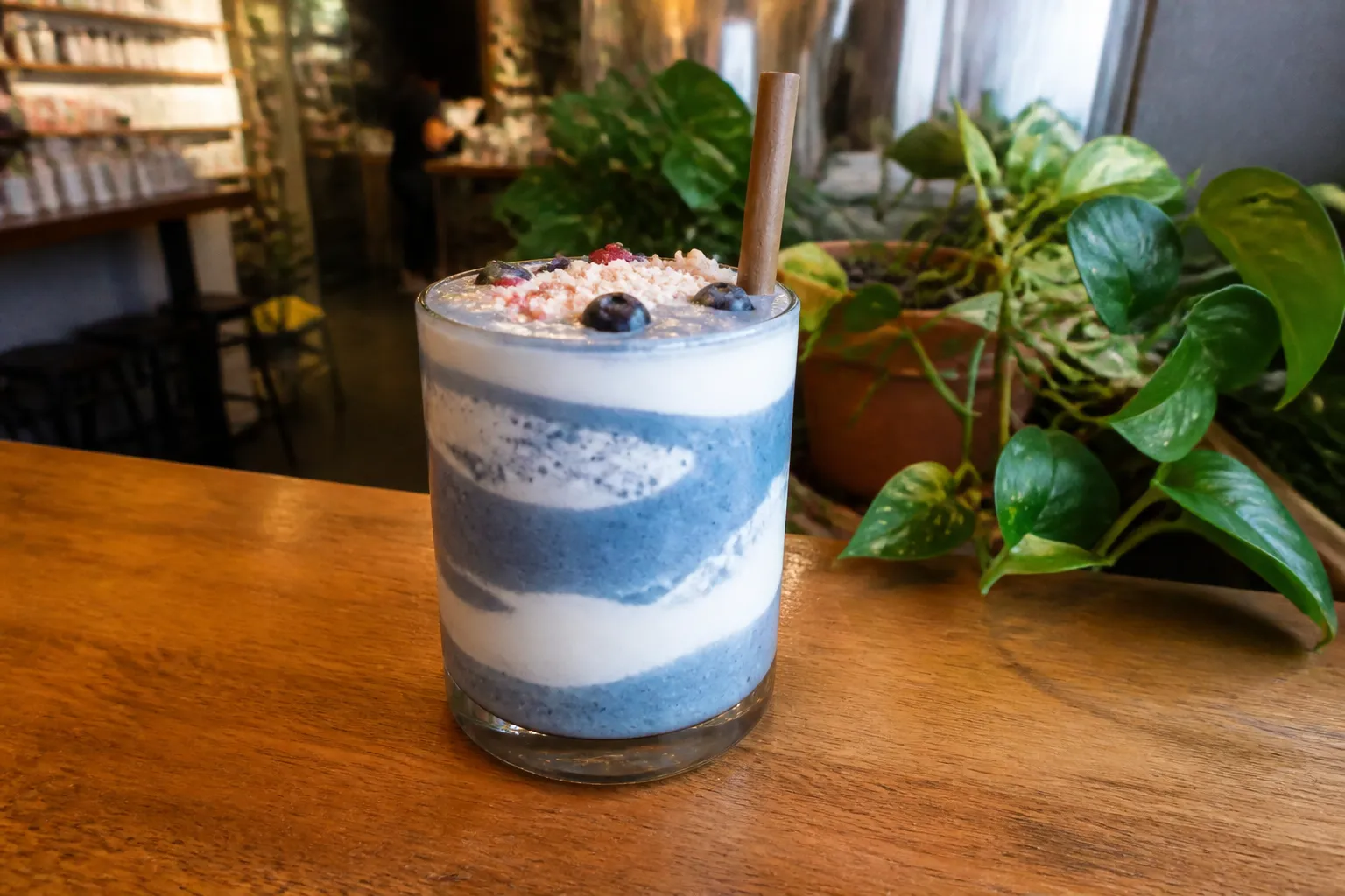 Layered blue spirulina smoothie on a wooden table at a New York juice bar.