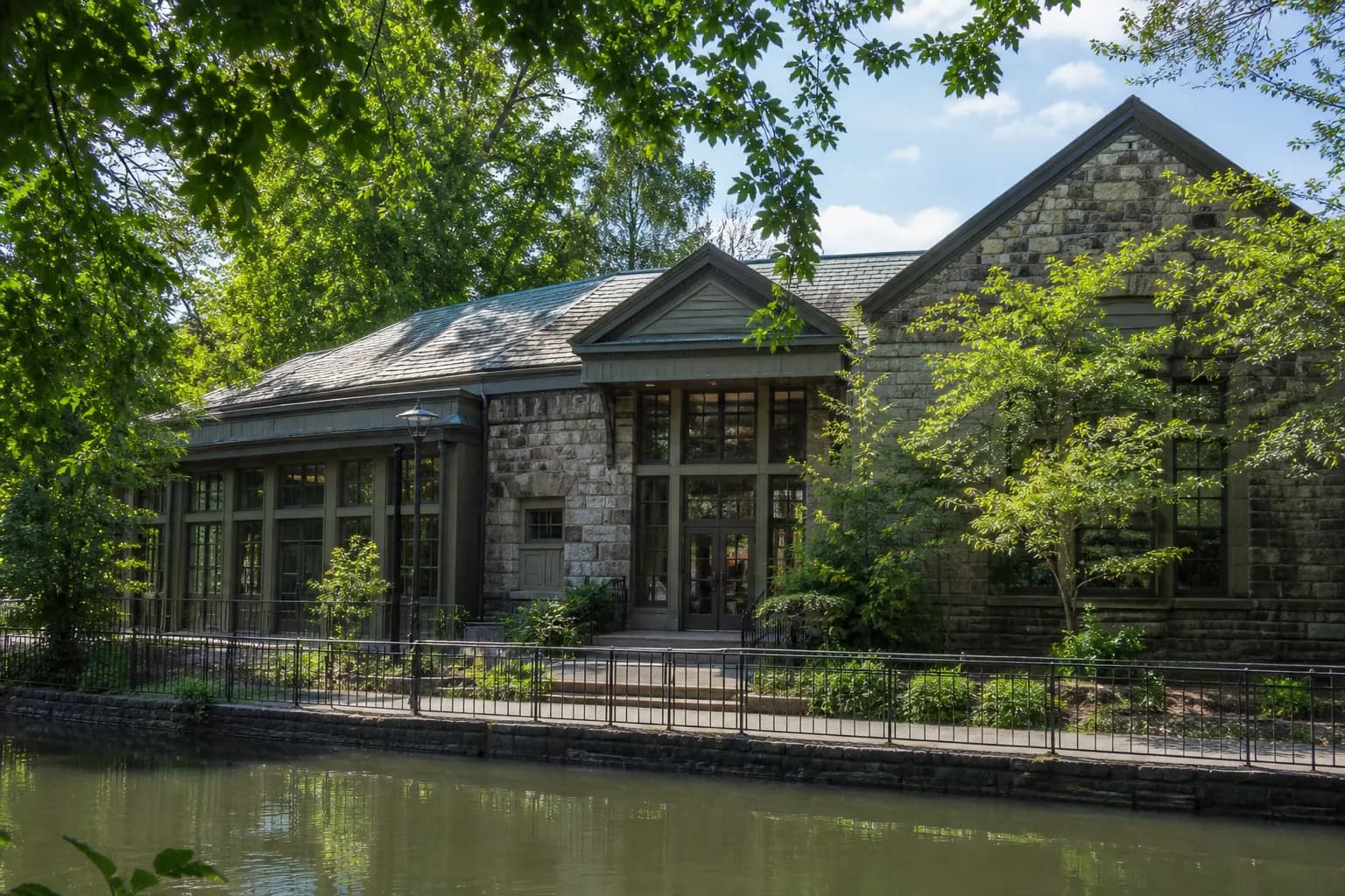 The stone facade of the Charles A. Dana Discovery Center at Central Park's Harlem Meer, framed by summer greenery.