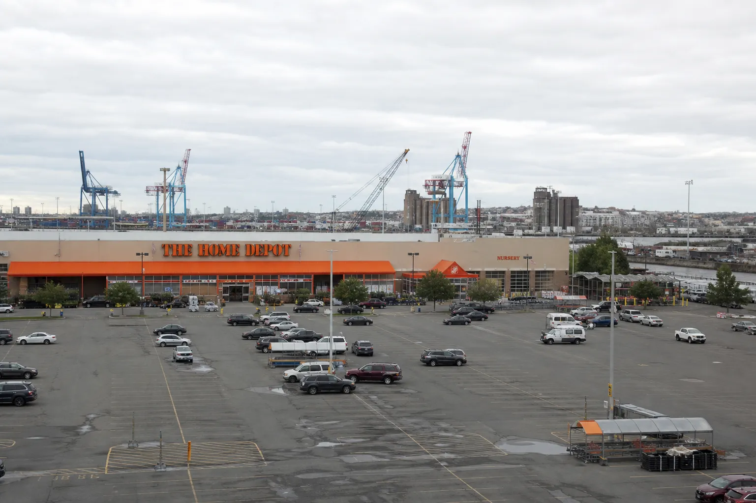 The exterior of the Red Hook Home Depot in Brooklyn, showing its massive flat-roofed warehouse design against a grey waterfront sky.
