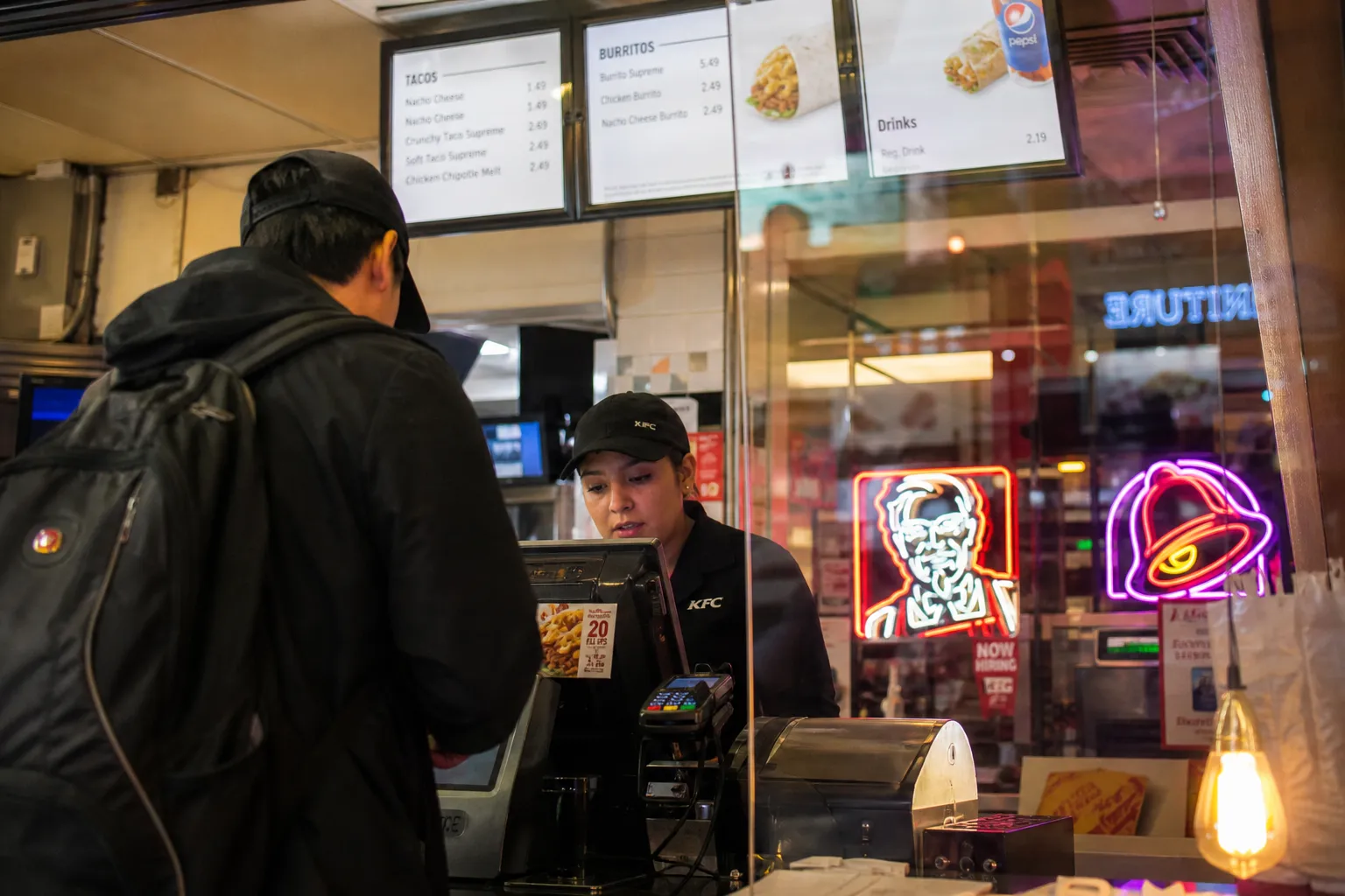 A customer ordering at the counter of a KFC and Taco Bell combo restaurant in Woodside, Queens.