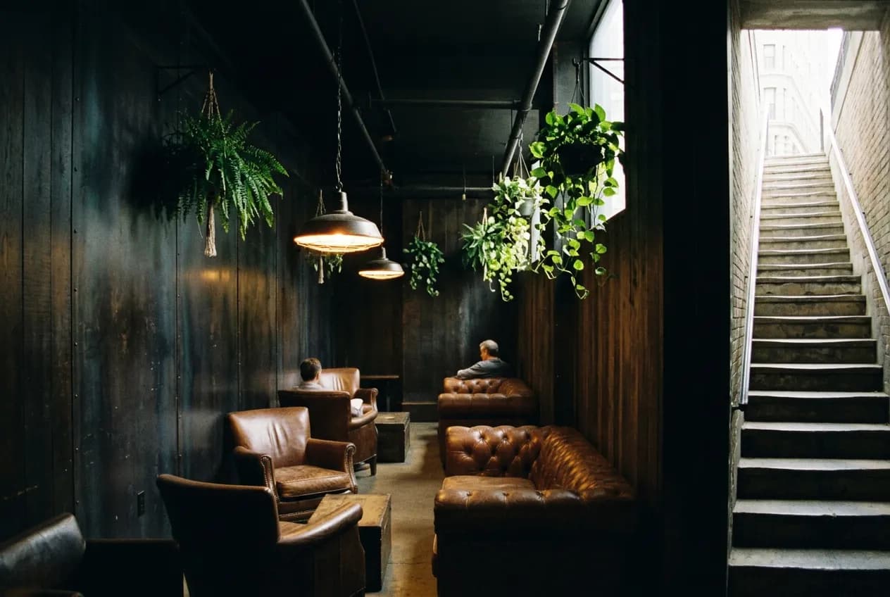A quiet subterranean lounge space with low lighting and plant-lined walls beneath street level