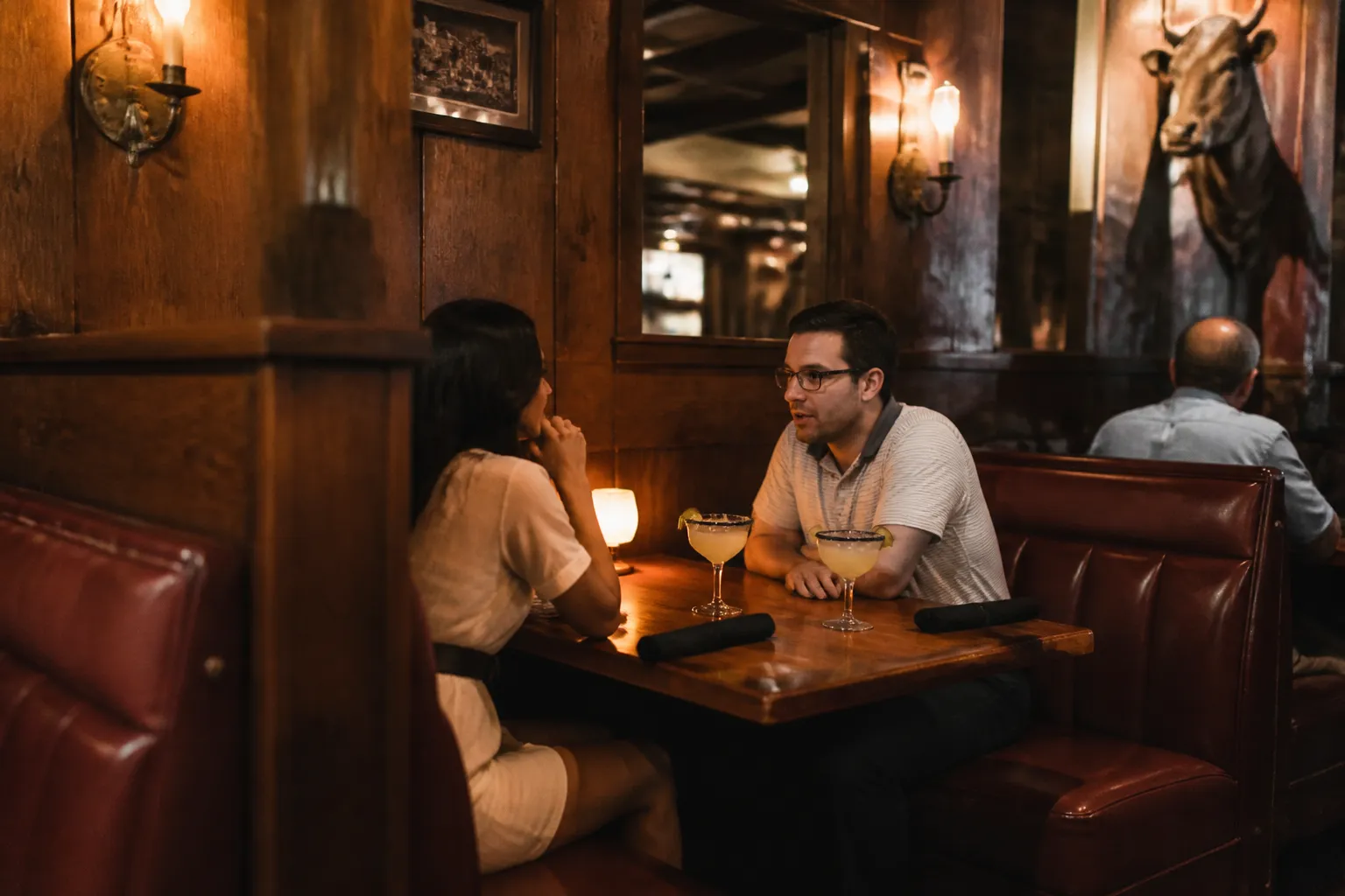 An intimate booth inside a steakhouse with warm wooden accents and classic cocktails on the table.