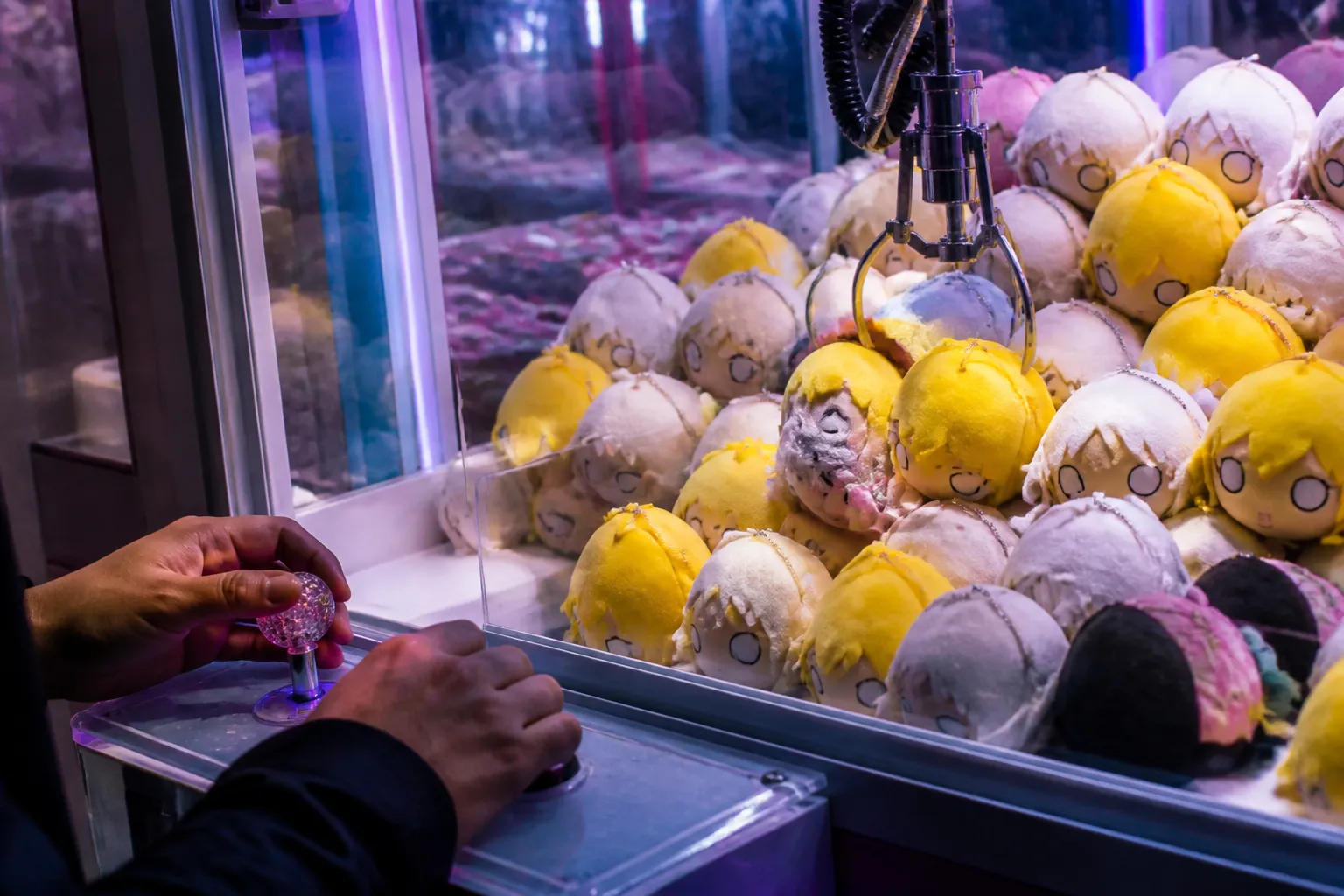 Close-up of a claw machine crane hovering over colorful plush toys inside the Flushing arcade.