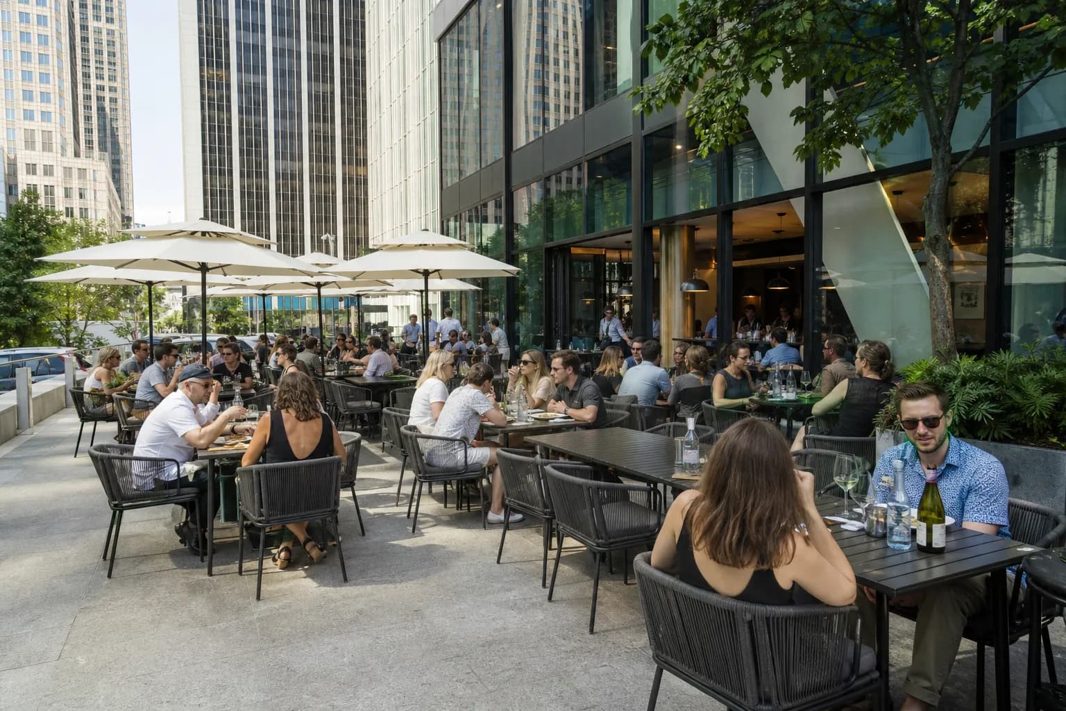 Outdoor dining patio of Sixty Vines Midtown Manhattan next to the Helmsley Building on a sunny day.