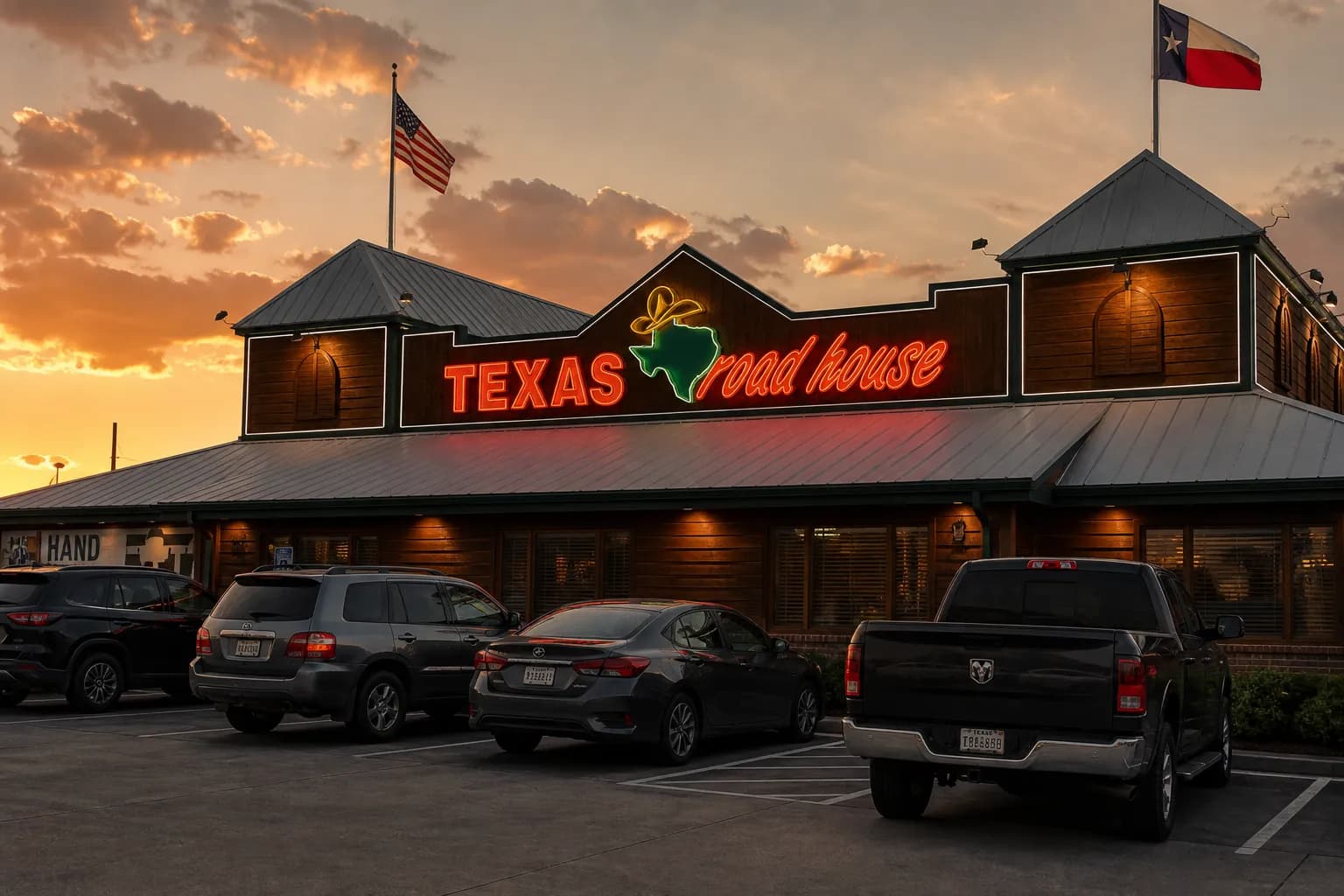 The distinctive rustic wooden storefront and bright neon sign of a Texas Roadhouse restaurant location lit up at dusk.