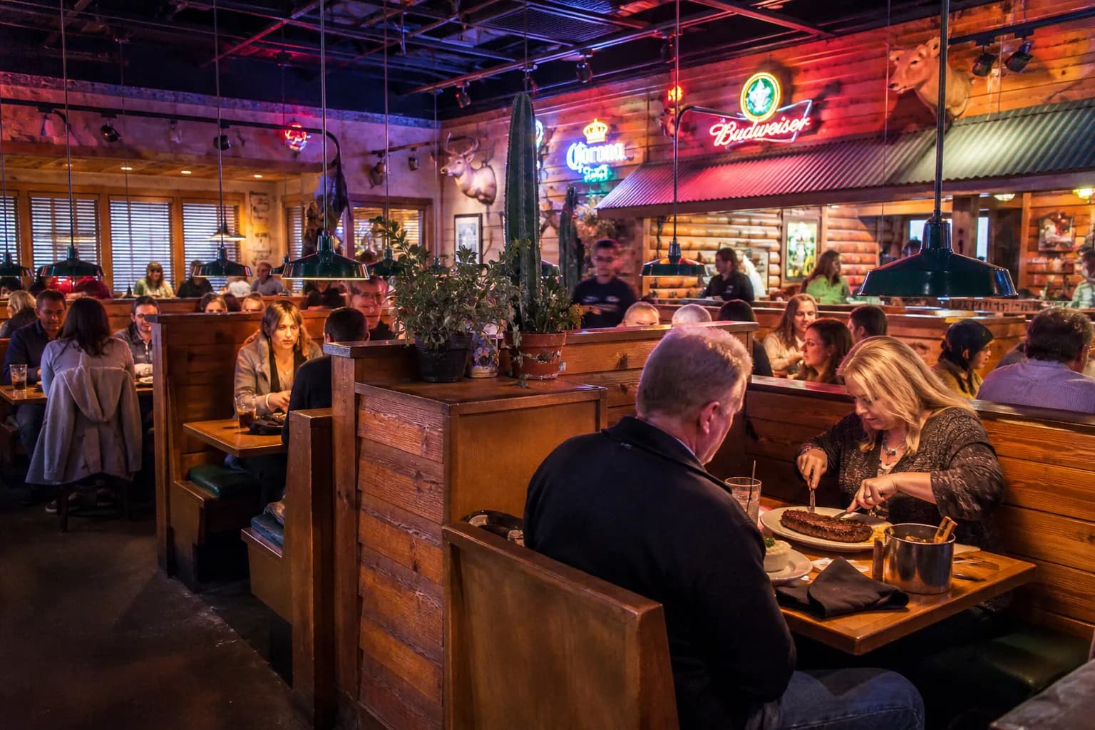 The bustling, rustic interior dining room of a Texas Roadhouse location in the evening.