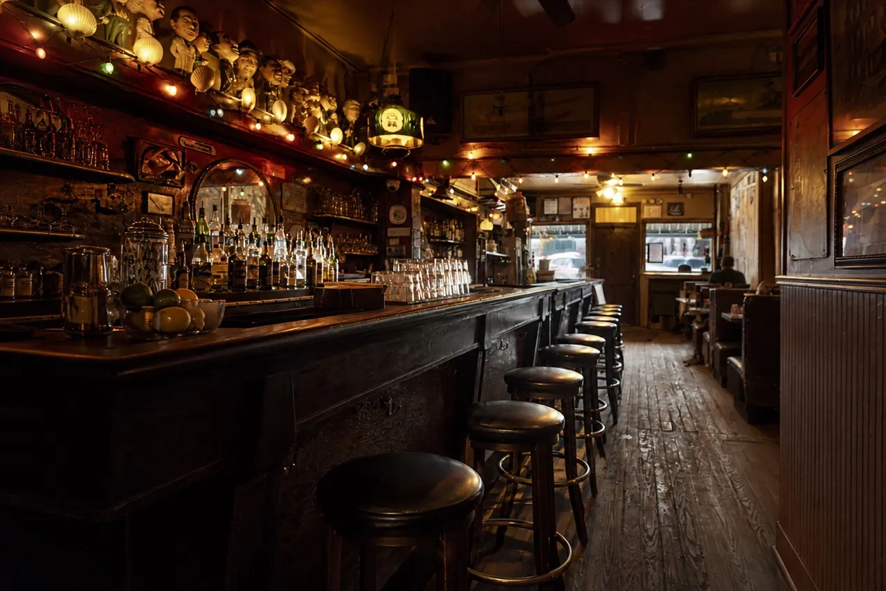 Old wooden bar counter with stools and bottles on the back shelf