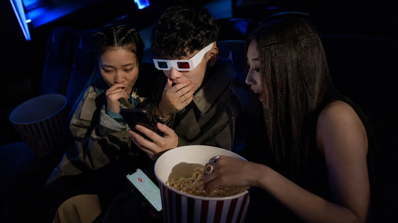 Friends in a cinema comparing an AI-created clip with a real-world night-out option