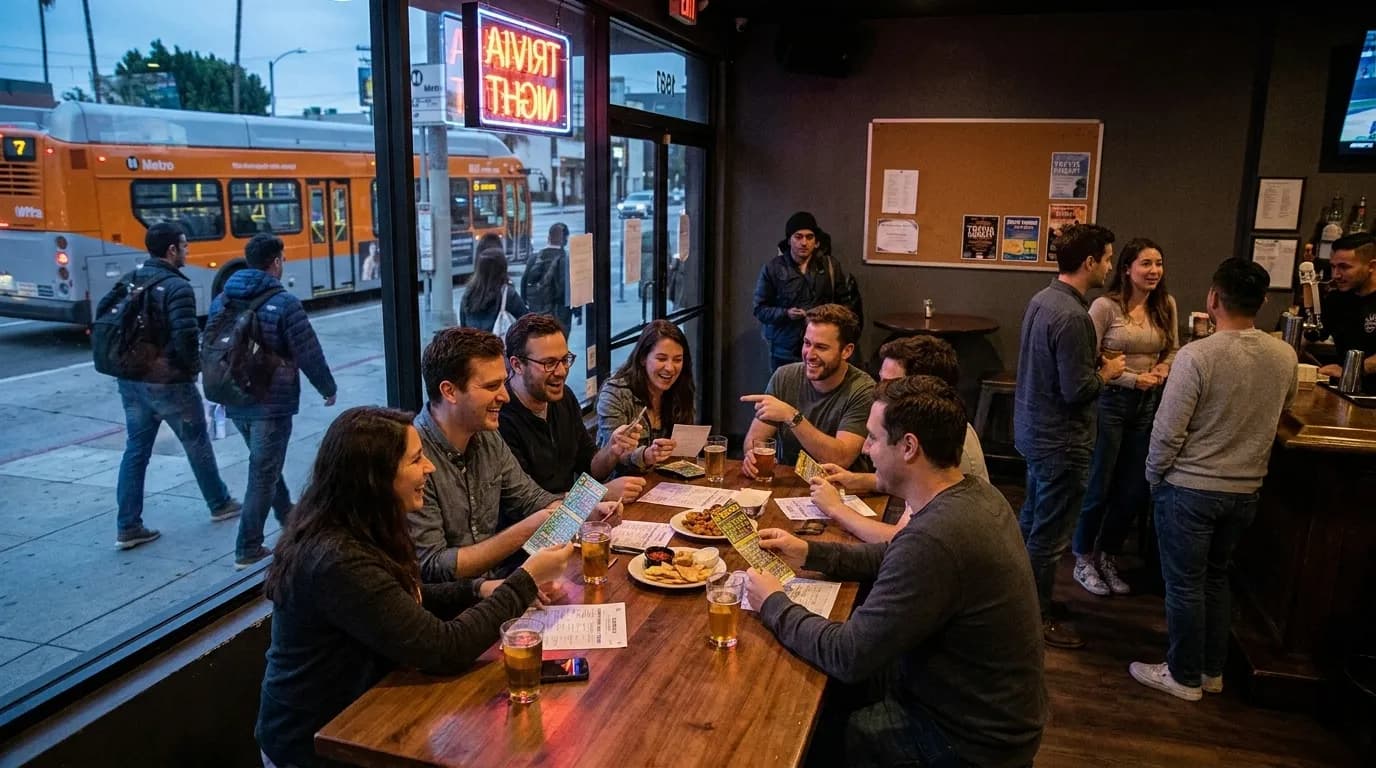 Trivia host holding microphone in front of chalkboard scoreboard at Los Angeles bar