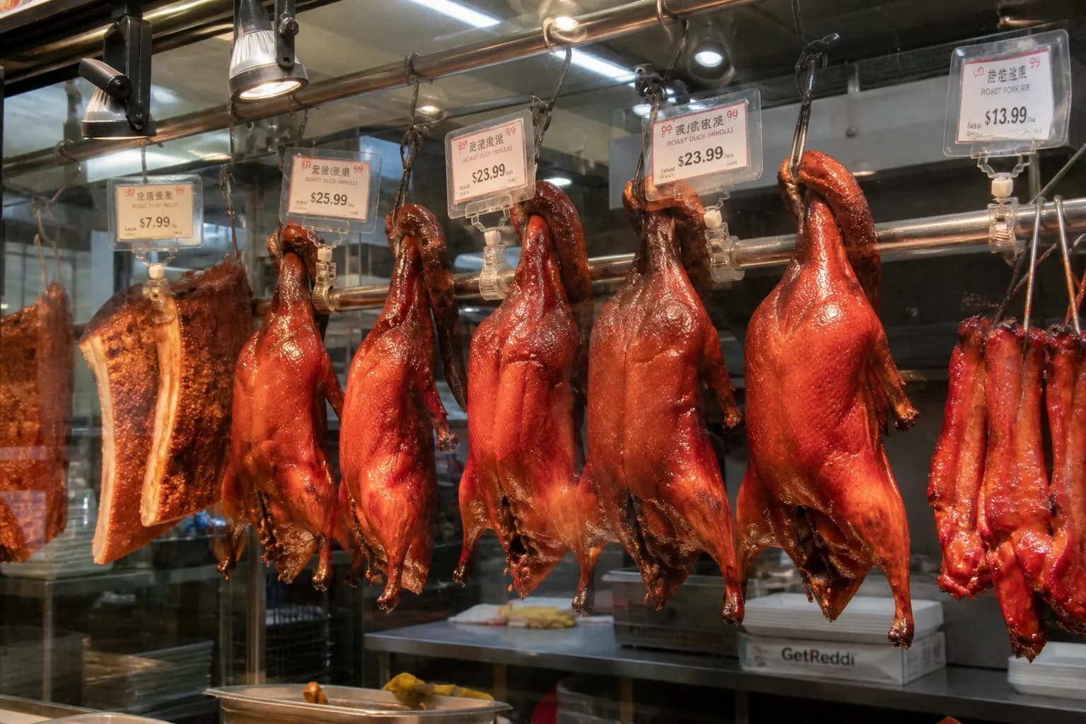 A wide shot of the bustling hot deli counter inside the Stonestown Galleria 99 Ranch Market in San Francisco, featuring hanging roast ducks.