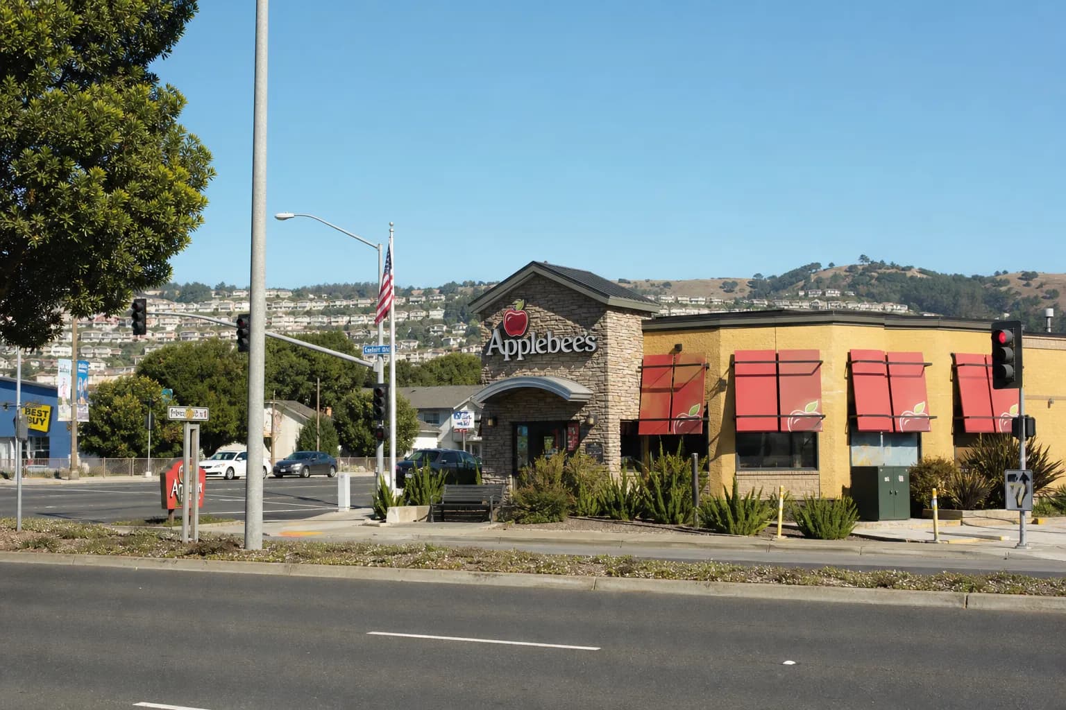A wide shot of a retail shopping center plaza in Daly City, California, during a clear late afternoon.