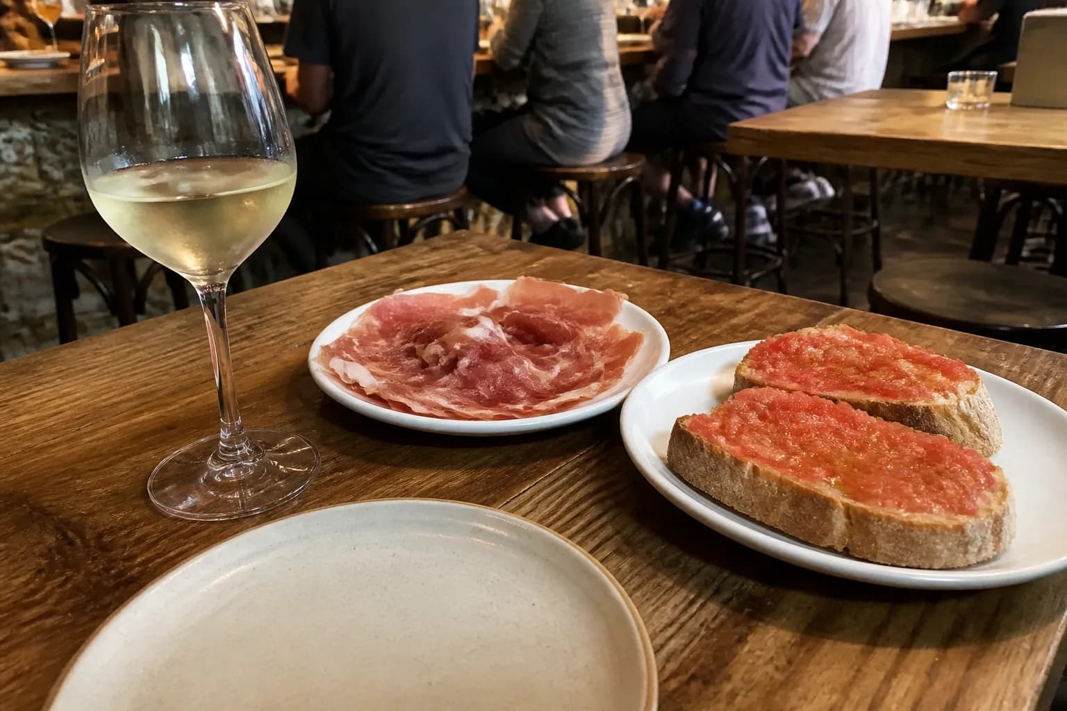 A vibrant table setting at Barcelona Wine Bar in San Francisco featuring plates of tapas, wine glasses, and warm ambient lighting.
