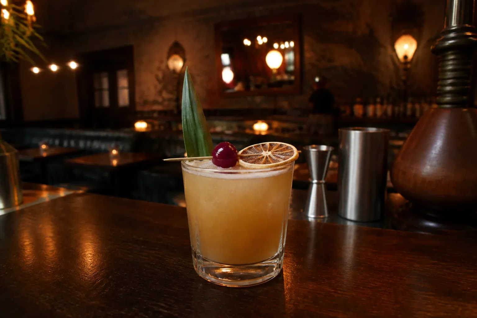 A close-up tabletop view of craft cocktails in condensation-beaded glasses on a dark wood bar in a San Francisco lounge