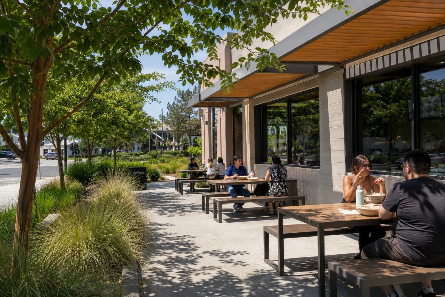 A bright, landscaped outdoor dining patio at a Peninsula quick-service restaurant on a sunny day.