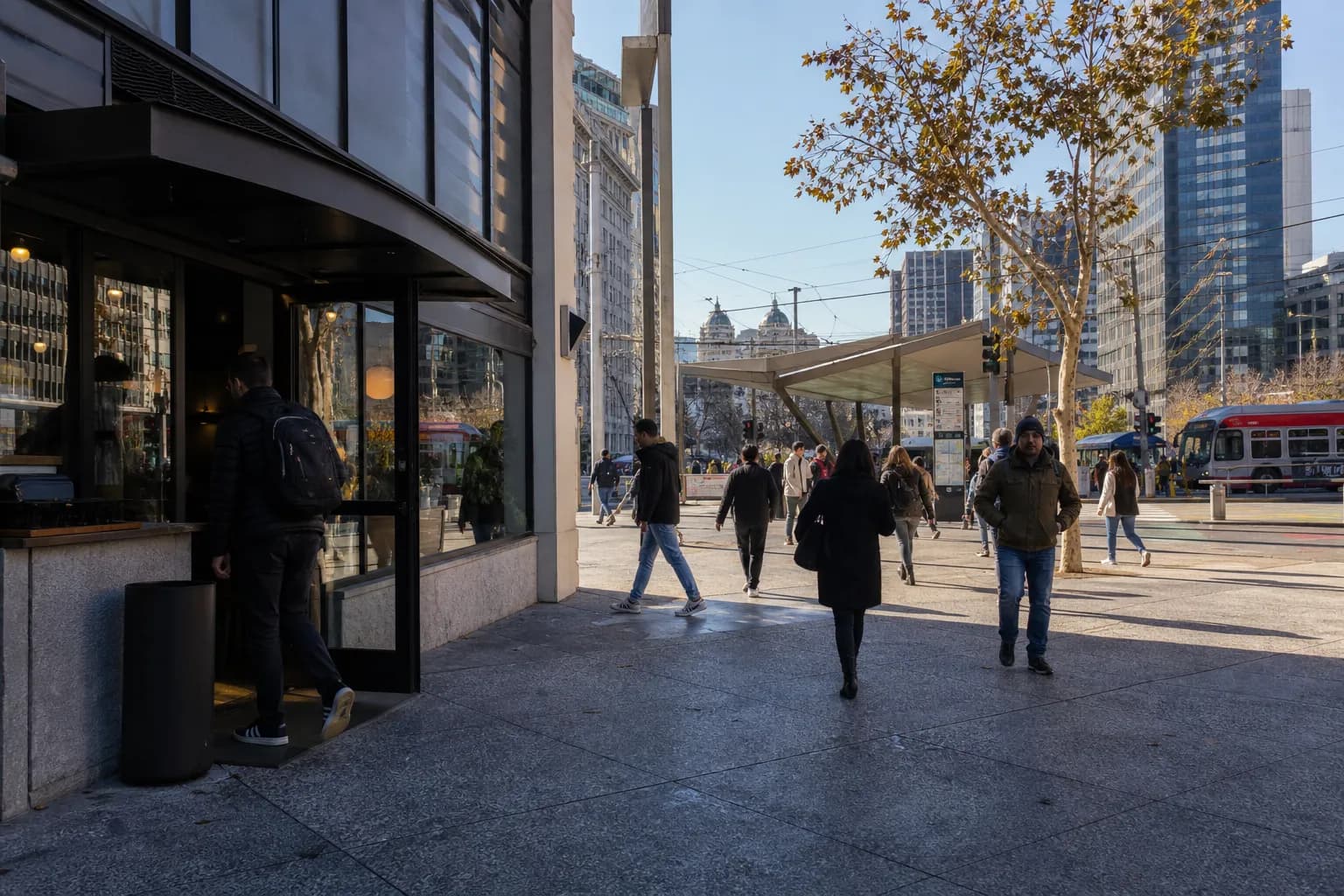 A bustling pedestrian street scene near Civic Center San Francisco with storefronts and transit riders.
