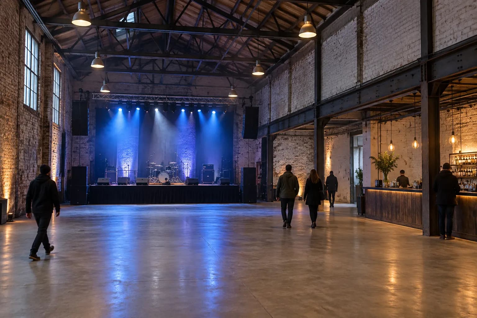 A high-ceilinged industrial main room with a stage lit at one end
