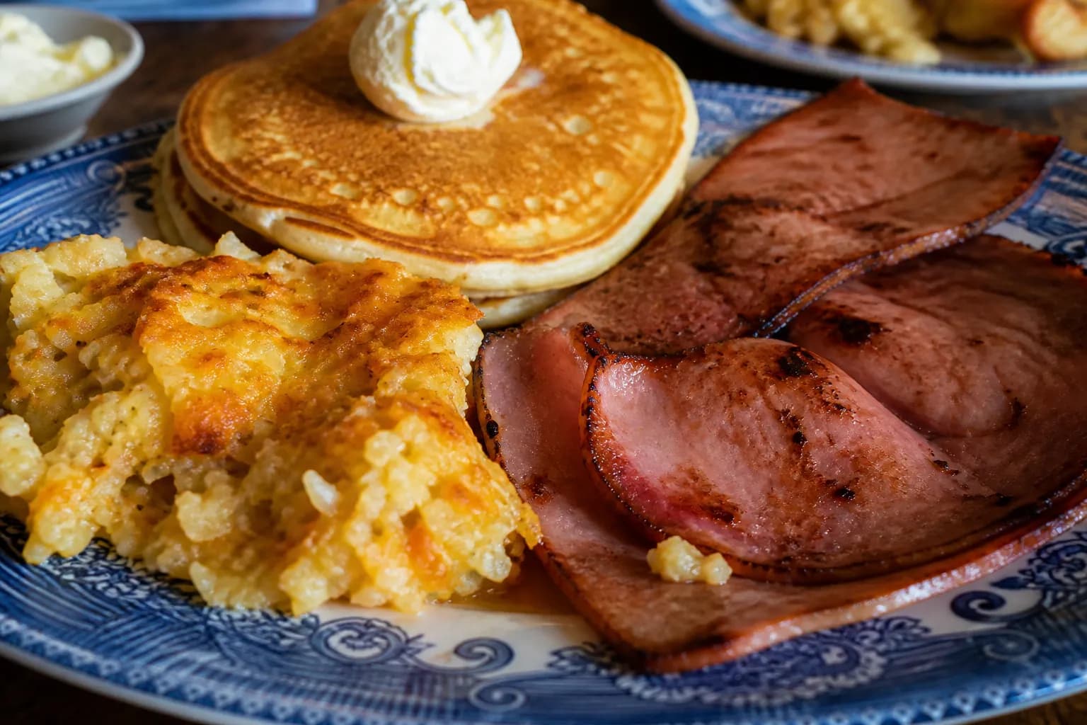 A hearty plate of Southern breakfast staples including hashbrown casserole and pancakes.