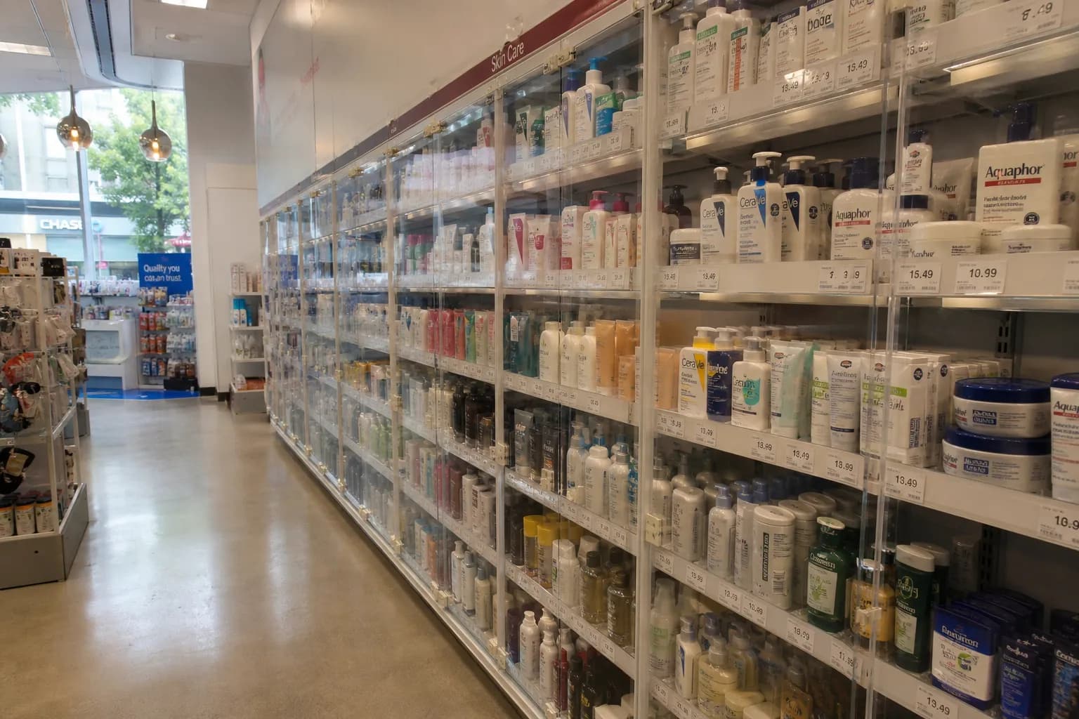 A perspective view of a clean drugstore aisle in San Francisco featuring locked security cabinets for personal care items.