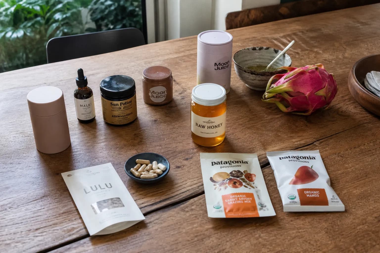 A flat-lay of premium organic supplements, raw honey, and fresh fruit on a wooden table.