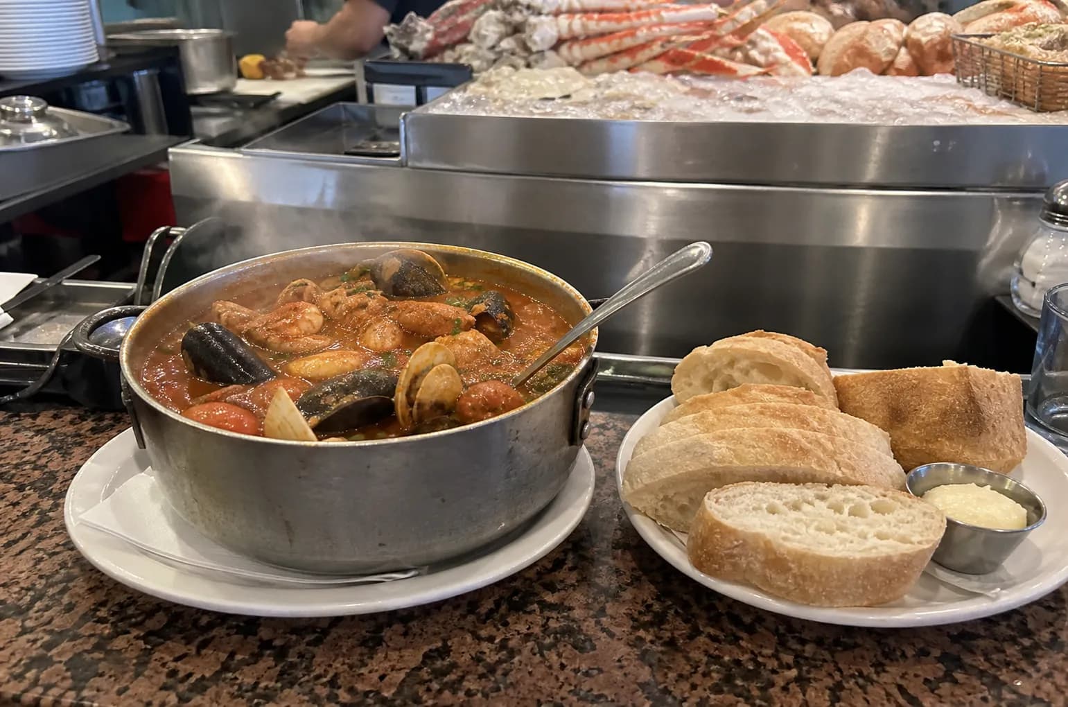 A pot of hot cioppino and sourdough bread at Sotto Mare counter.