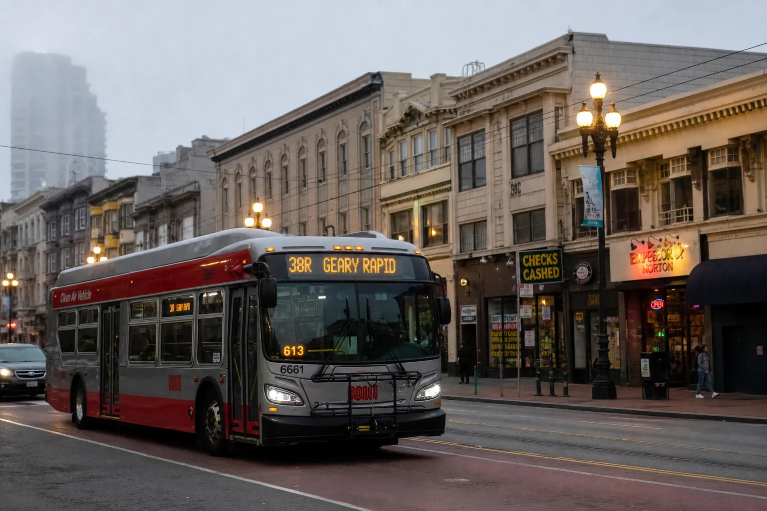 A classic red San Francisco Muni bus traveling down Geary Boulevard on a foggy afternoon near local storefronts.