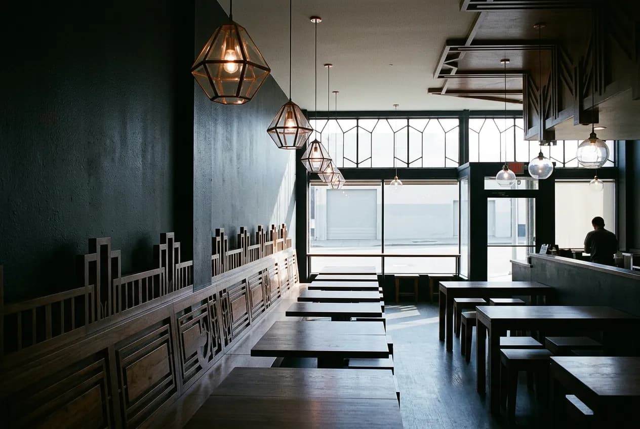 Empty dim ramen dining room with wooden benches and dark walls before evening service
