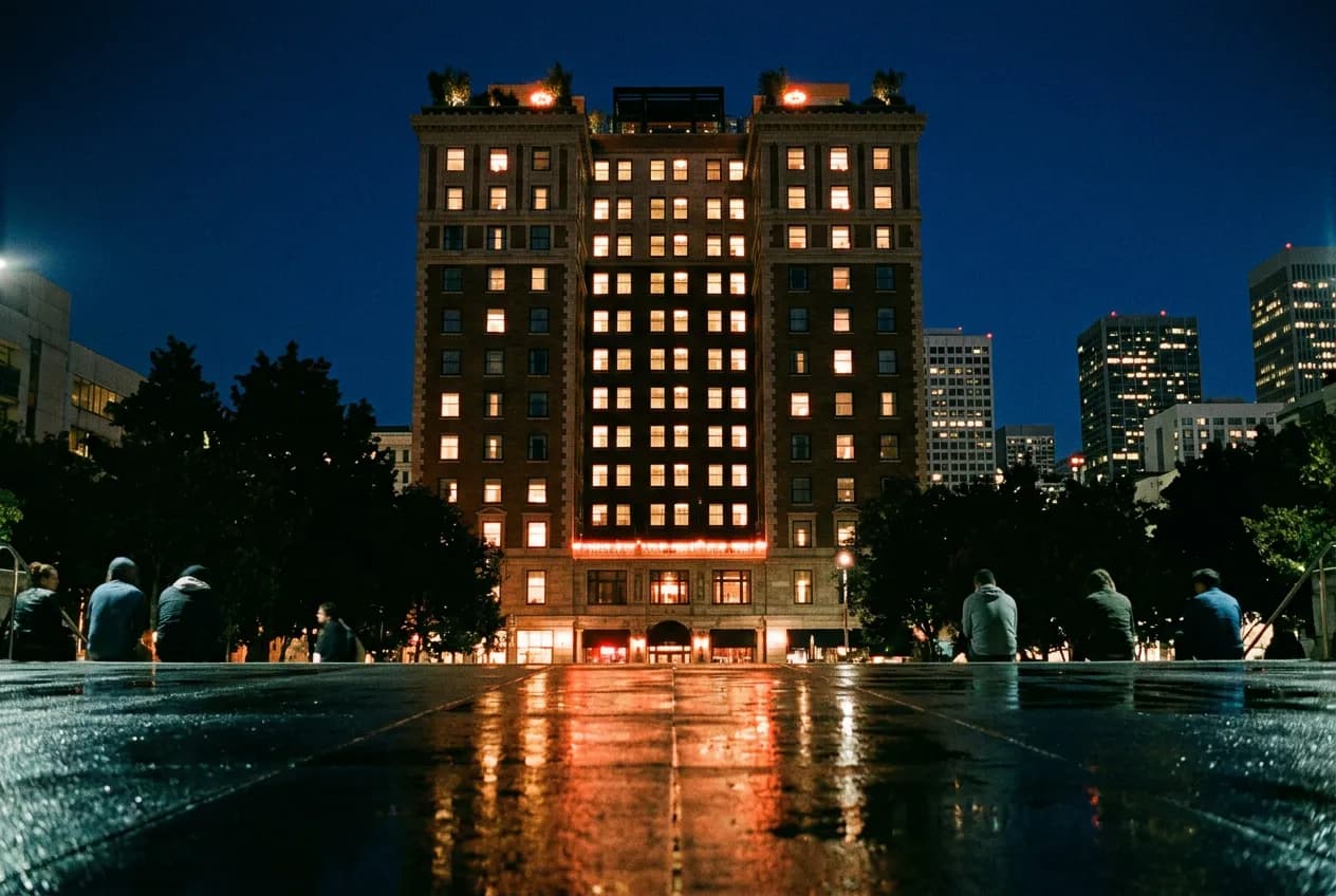 Night view of a SoMa hotel tower with warm light spilling from its upper floors onto a quiet 4th Street