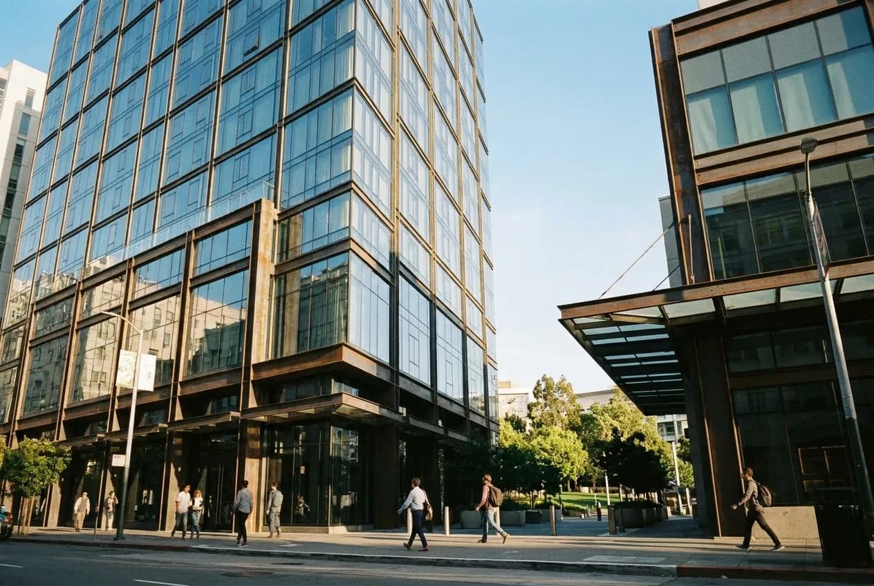 Virgin Hotel San Francisco exterior on 4th Street, twelve-story glass and steel building in SoMa, pedestrians on sidewalk, afternoon light, Yerba Buena Gardens visible nearby.