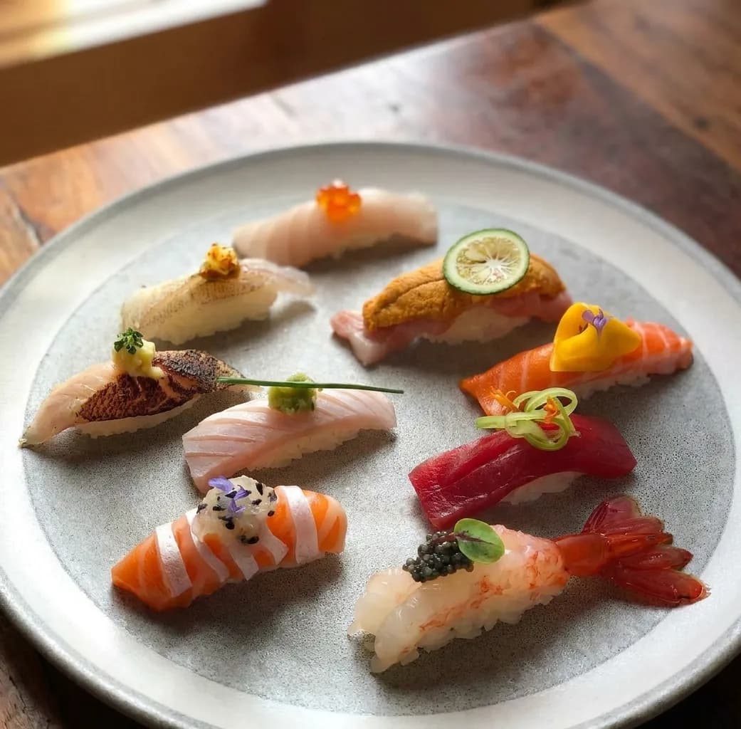 Assorted nigiri sushi selection arranged on a stone ceramic plate in natural window light at an East Village sushi bar