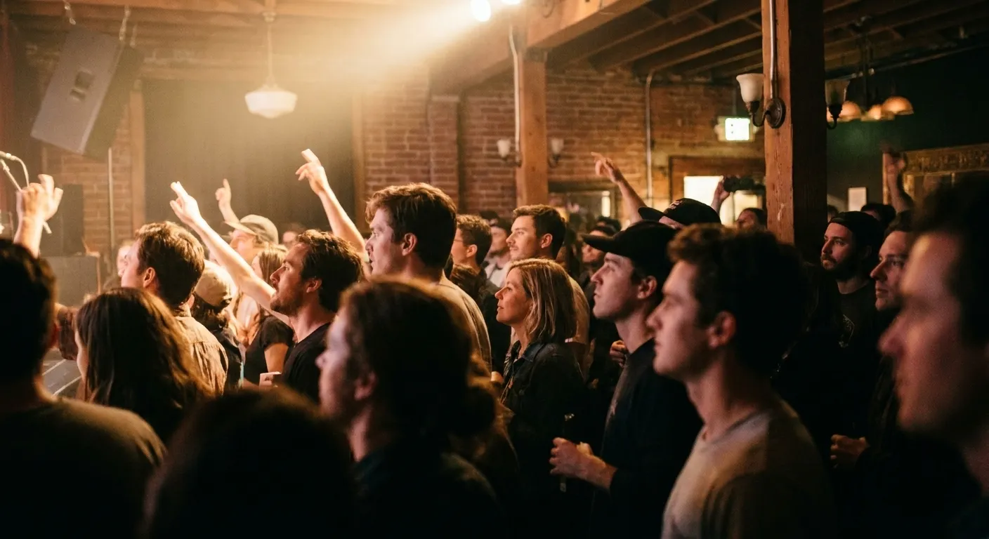 A packed standing crowd at a small San Francisco venue with stage light spilling over the room