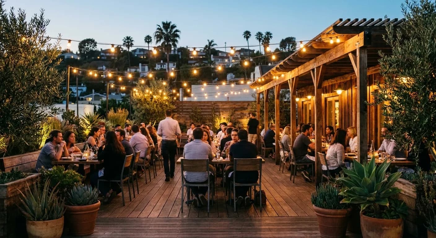 An outdoor restaurant patio filling up under string lights in the early evening