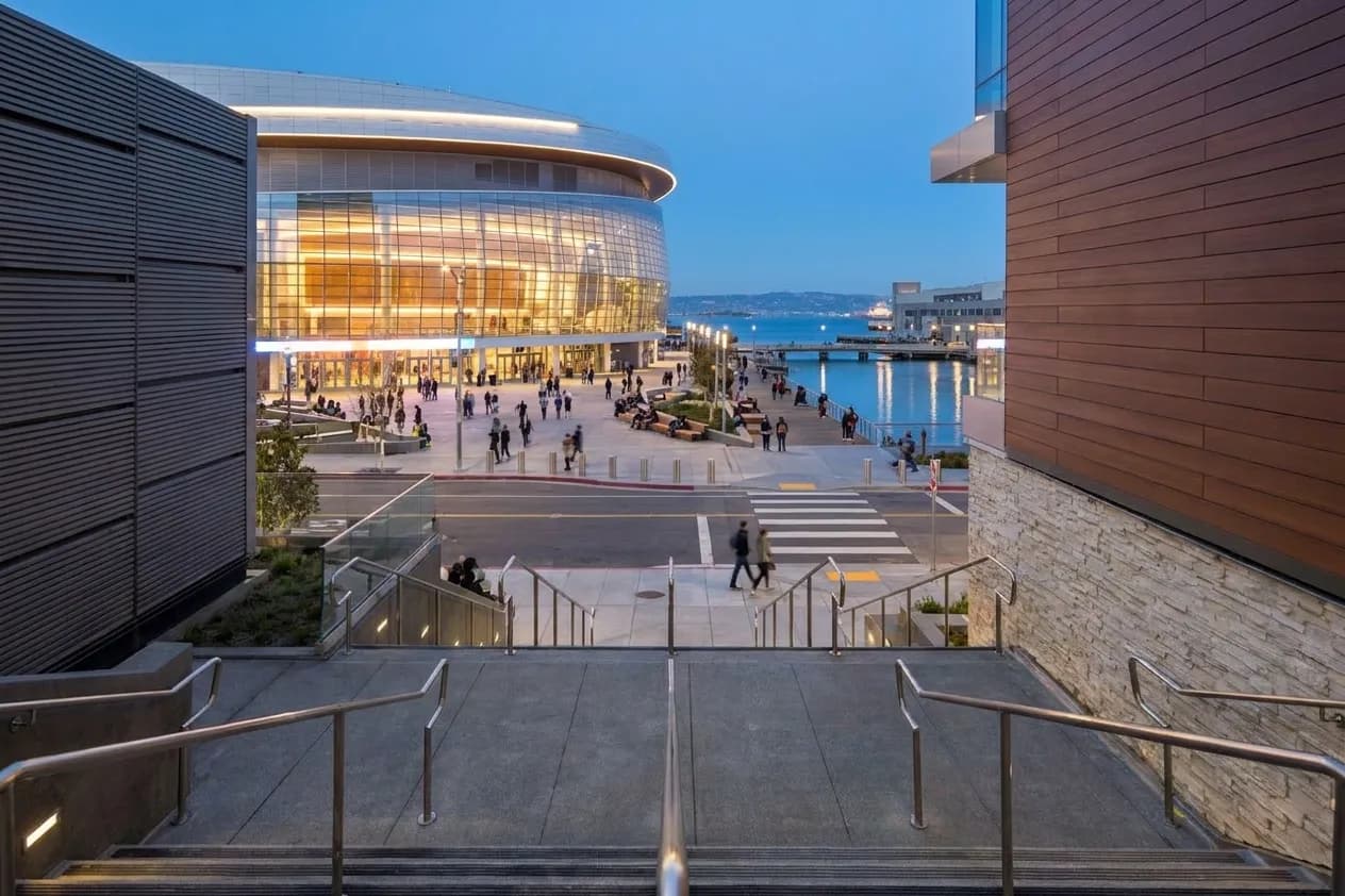 Chase Center exterior at dusk with Thrive City plaza and waterfront visible in Mission Bay