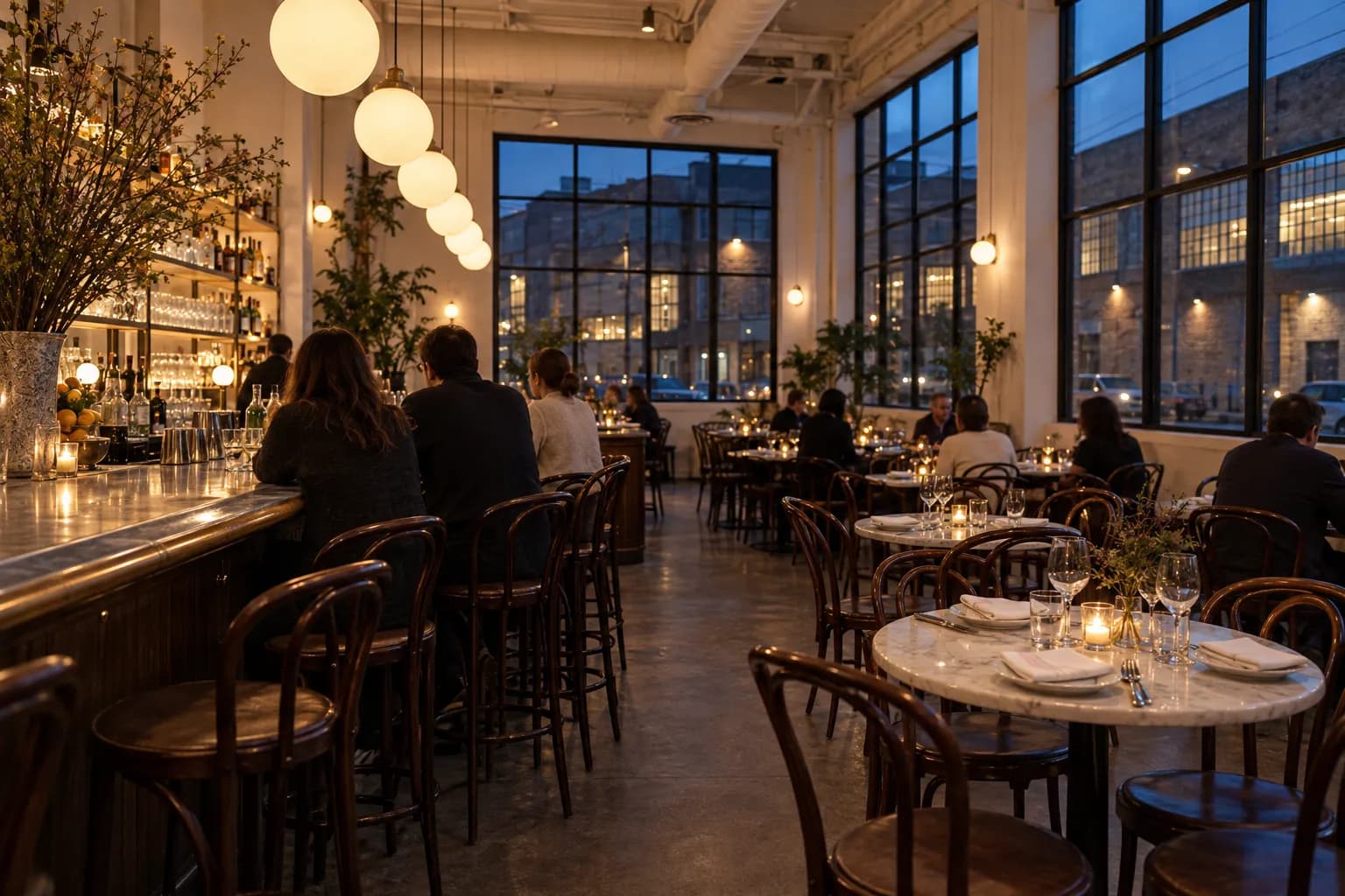 A bright high-ceilinged corner bistro with a long bar and large windows