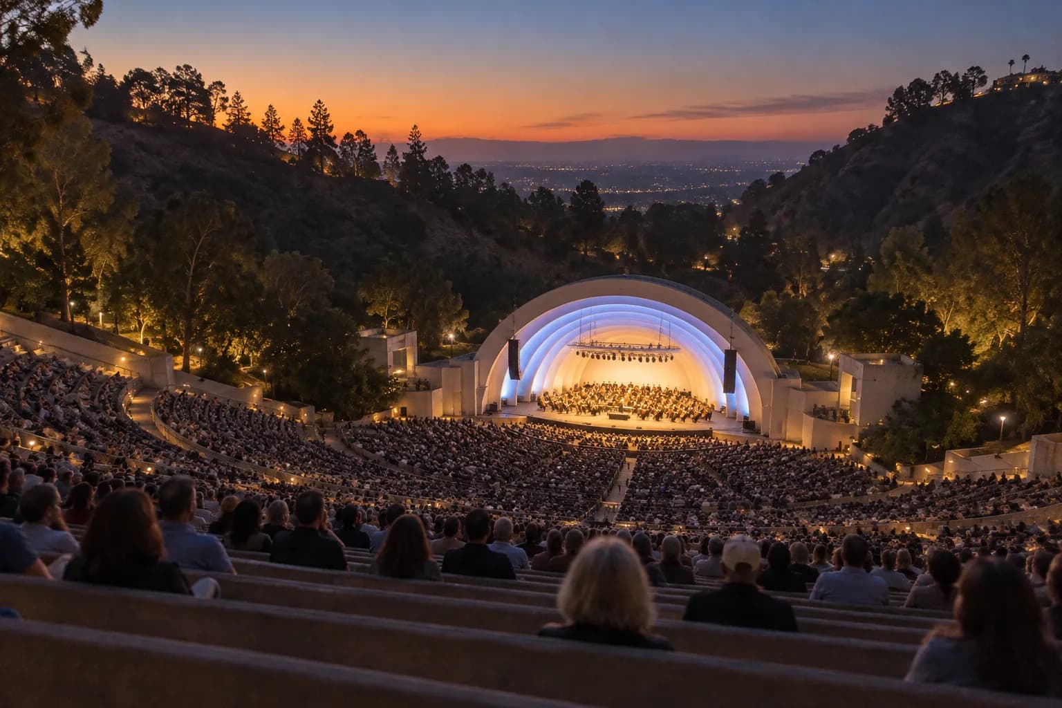 A large outdoor amphitheatre in a canyon at dusk with a lit shell stage