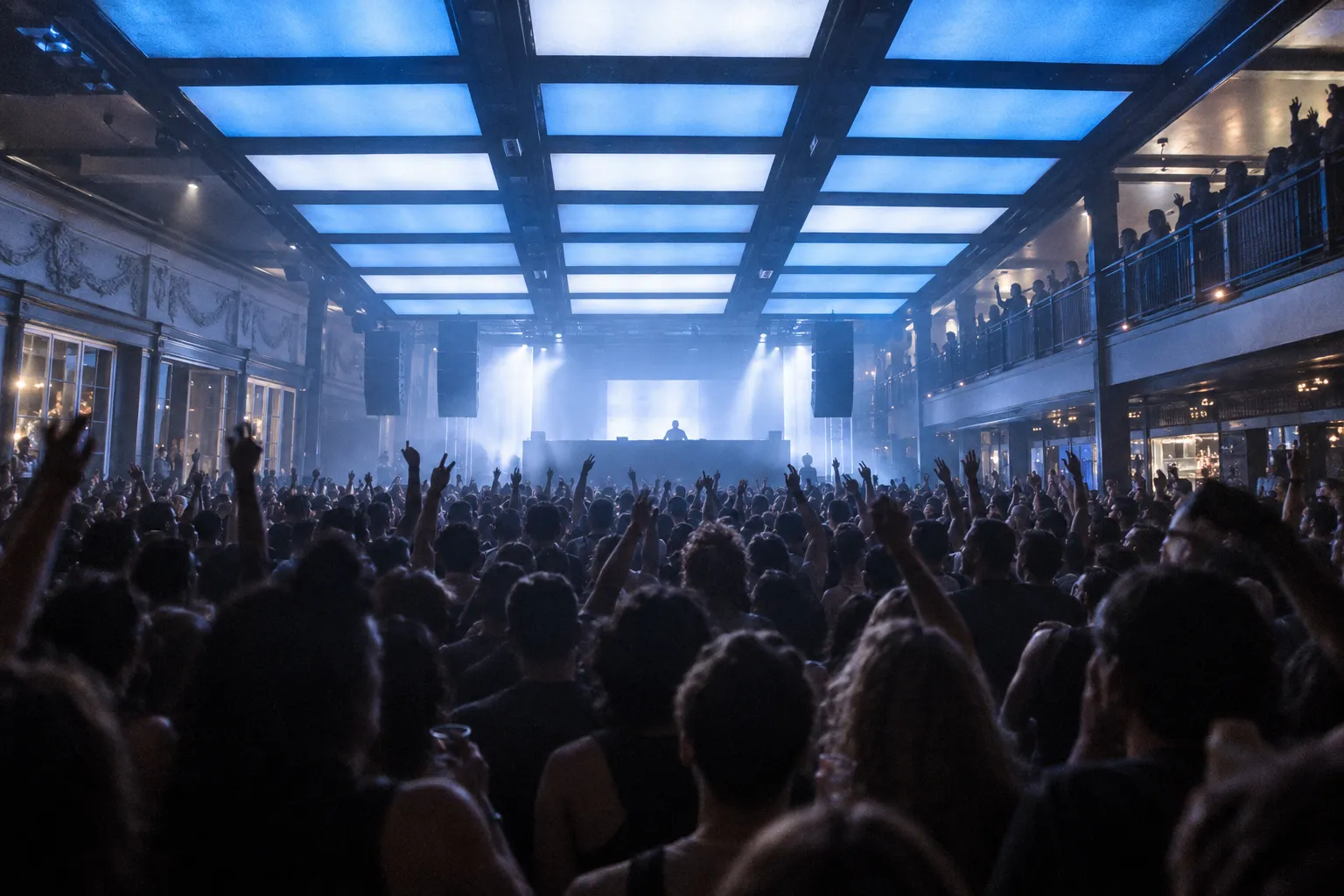 A large club floor beneath lit ceiling panels and moving lights