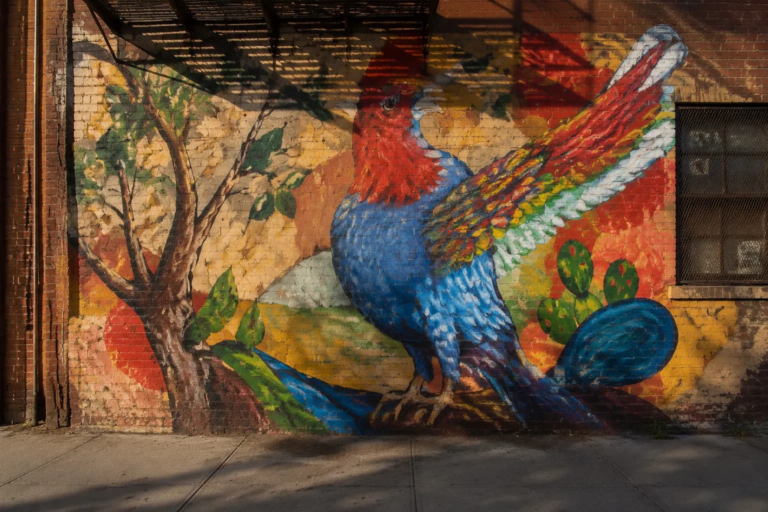 Colorful street mural on brick wall in Bushwick, Brooklyn, with sidewalk and afternoon shadows
