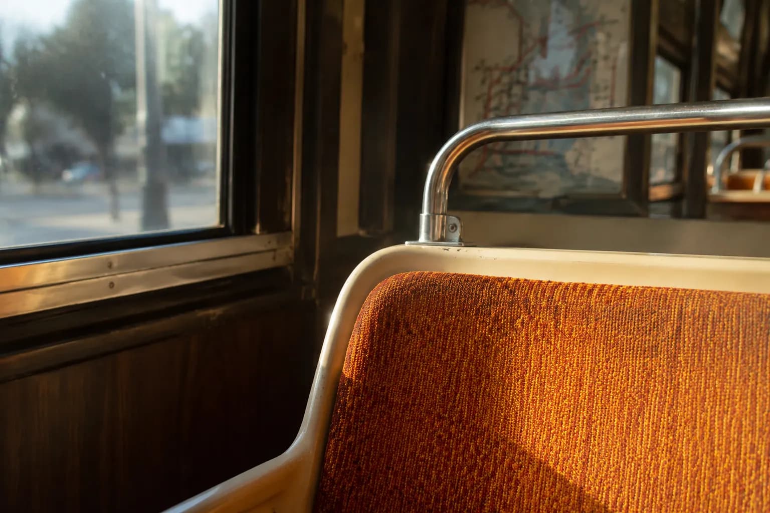 Interior detail of a J-Church Muni streetcar in San Francisco, showing worn seats and handrail in natural light