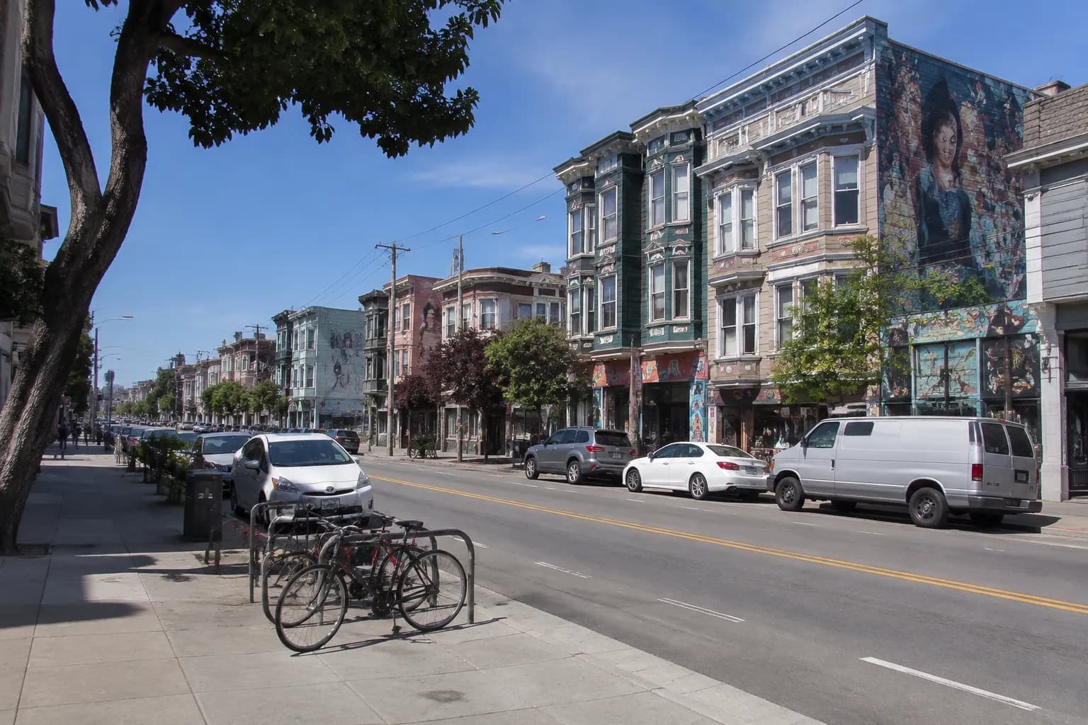 Valencia Street in the Mission District, San Francisco, on a clear afternoon with murals and storefronts lining the block