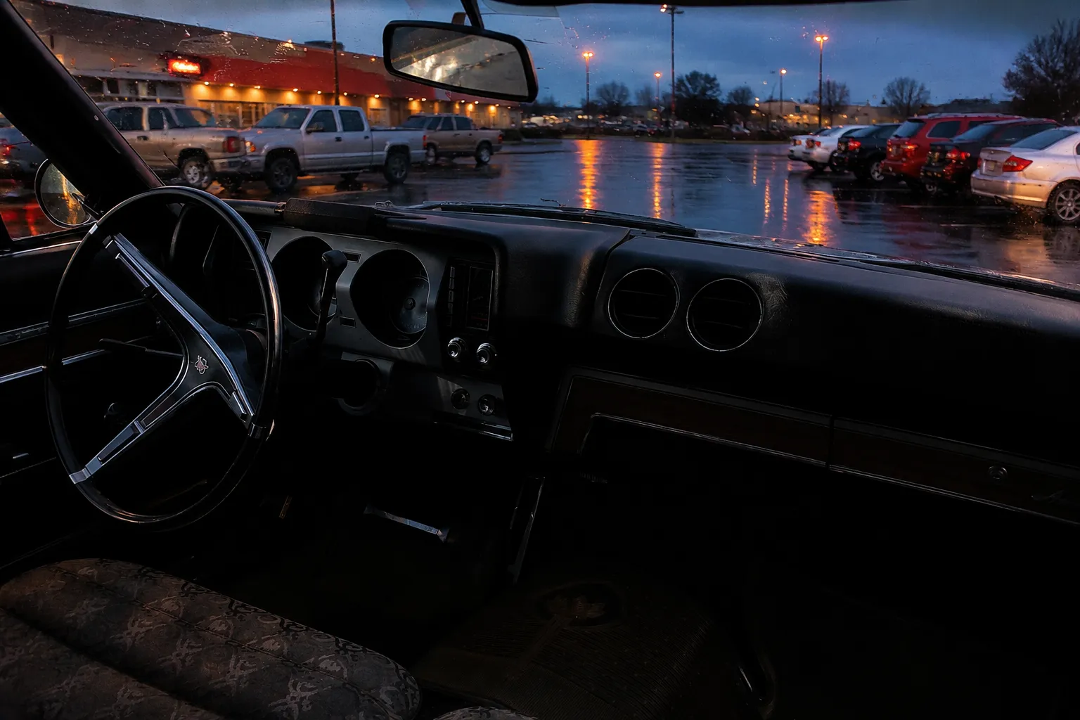View through car windshield of Miami restaurant parking lot at dusk after rain