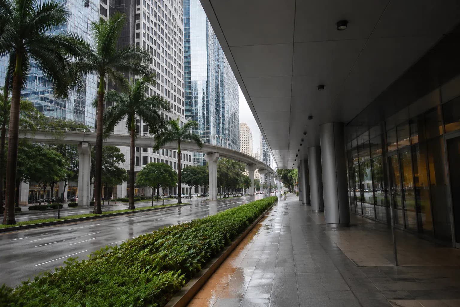 Covered sidewalk along Brickell Avenue in Miami with high-rises and palm trees on a summer afternoon