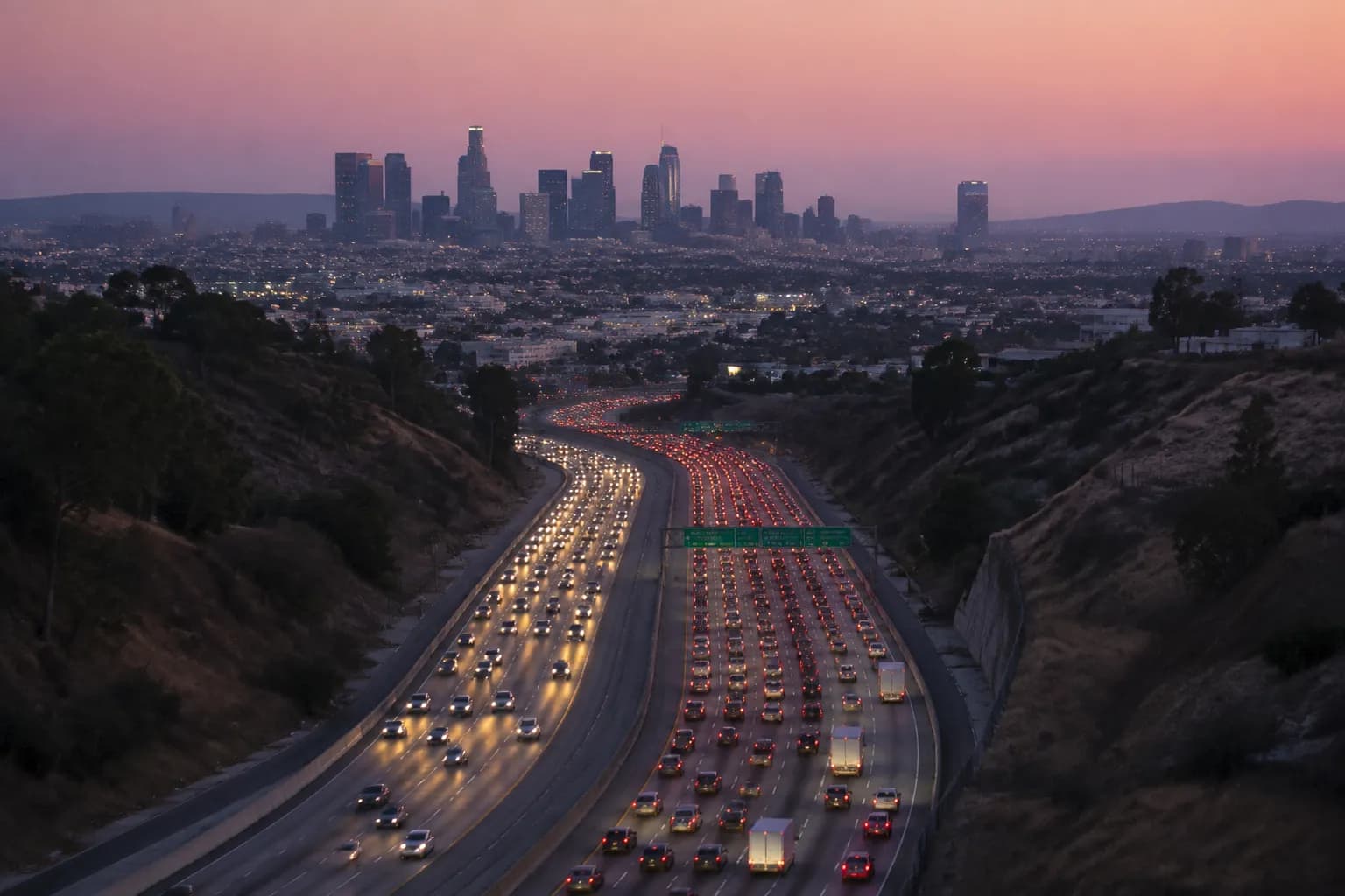 Evening traffic on Interstate 5 freeway in Los Angeles with light trails and downtown skyline in the distance