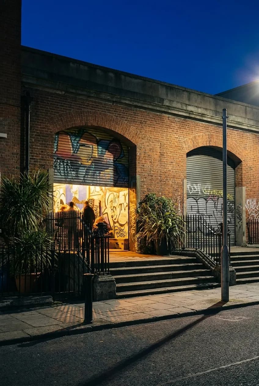 Open warehouse bay door in Wynwood at night with warm interior light spilling onto sidewalk