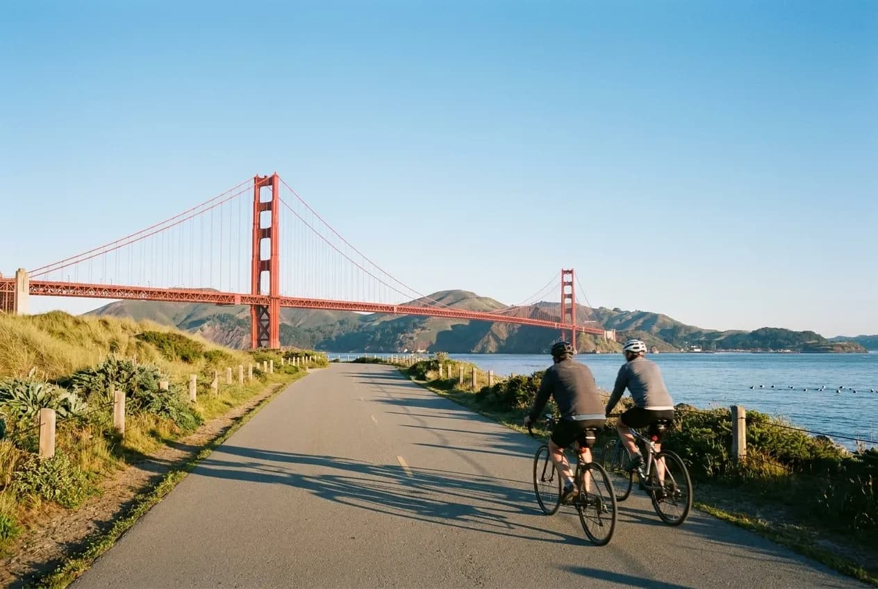 Cyclists on the Crissy Field bike path approaching the Golden Gate Bridge on a clear San Francisco morning